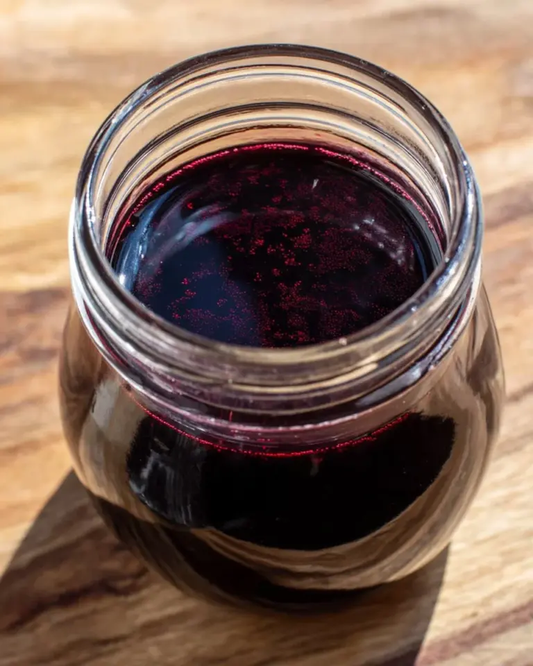 Homemade blueberry simple syrup in a glass bottle.