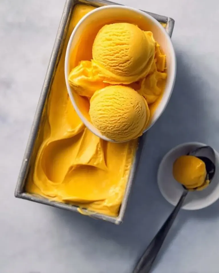 Homemade summer mango ice cream in a bowl topped with fresh mango slices