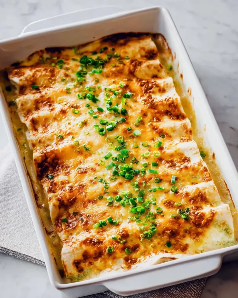 Cheesy chicken enchiladas topped with white sauce, served on a plate