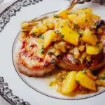 Skillet pork chops with apples and pan sauce served on a plate.