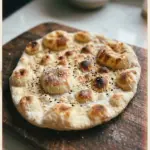 Freshly made stretchy flatbread on a wooden surface